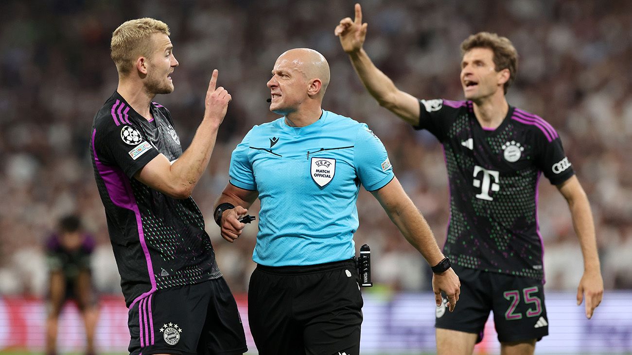 Matthijs de Ligt and Thomas Müller protest to referee Szymon Marciniak